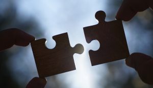 Zwei Hände stecken Puzzlesteine zusammen
