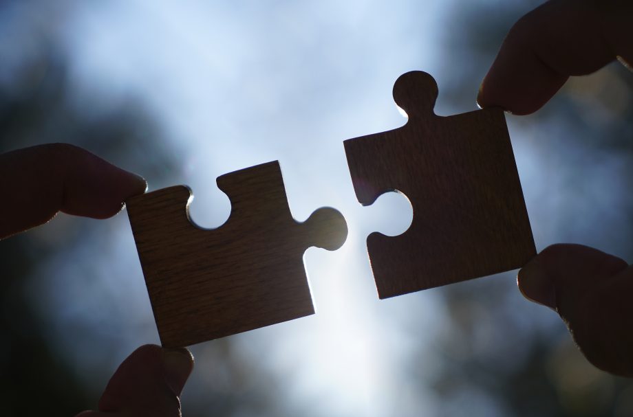 Dapper Labs integriert Stablecoin FUSD in die Flow Blockchain Zwei Hände stecken Puzzlesteine zusammen