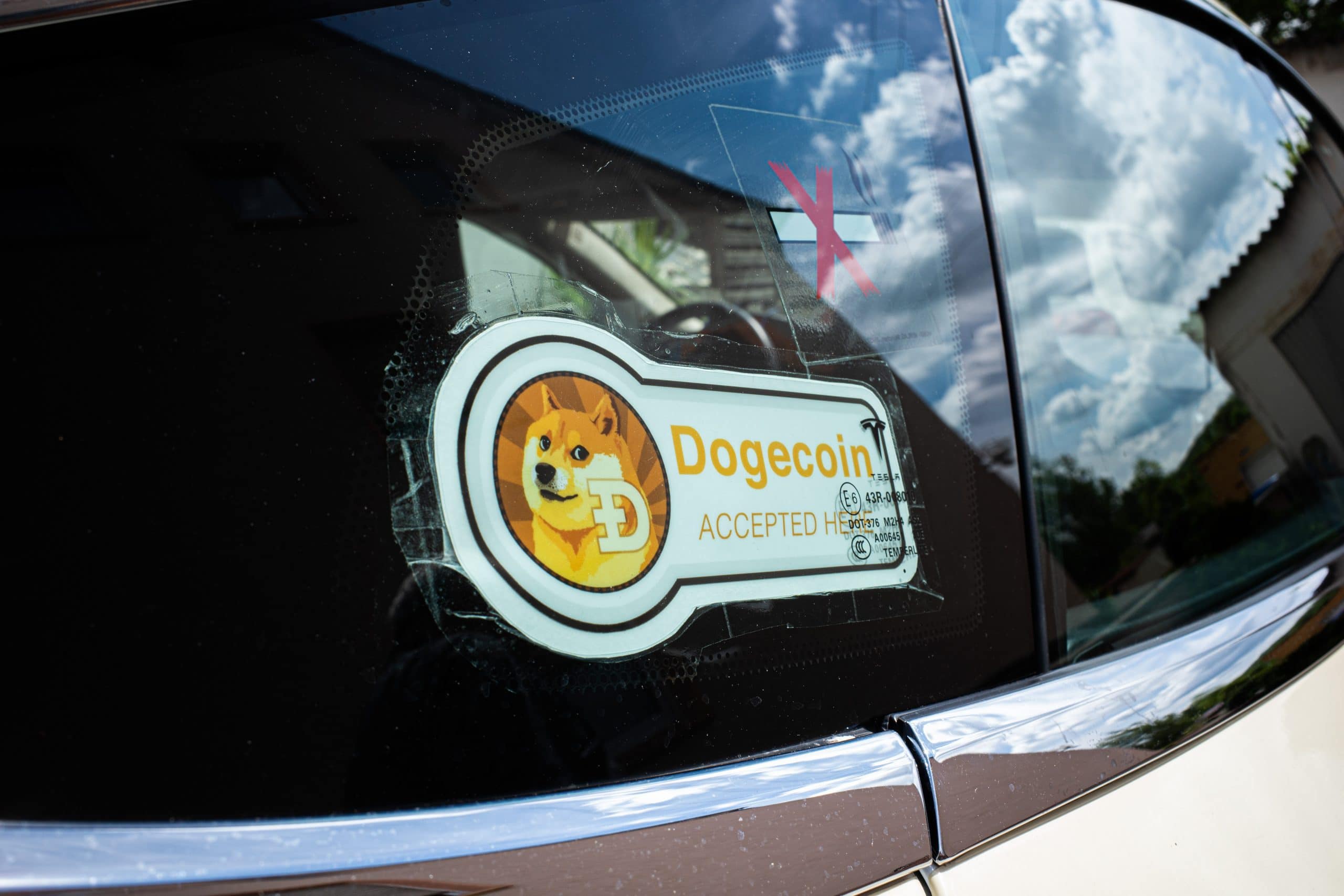 Das Dogecoin-Banner auf einer Autofensterscheibe.