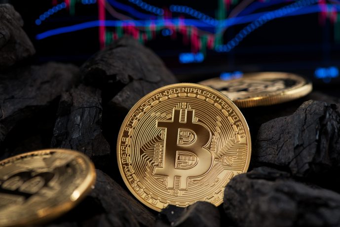 Bitcoin-Münzen und Kohle vor Chart-Hintergrund