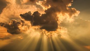 Lichtstraheln durchbrechen eine Wolke.