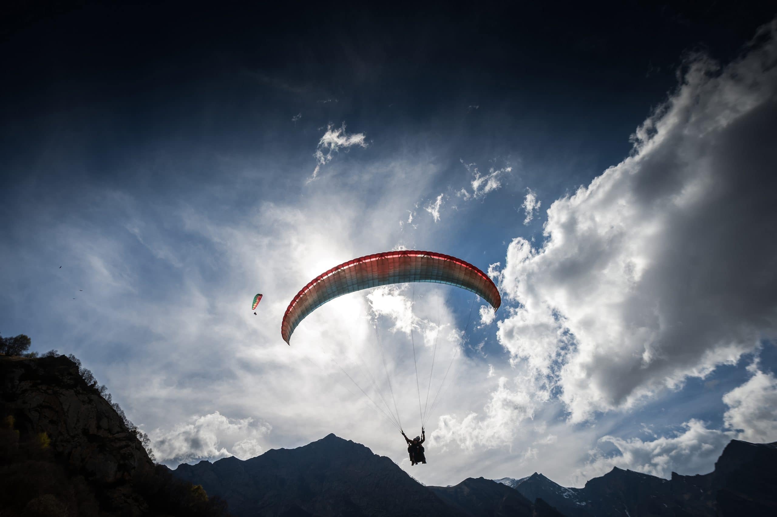 Ein Paraglider fliegt knapp über einen Berg.