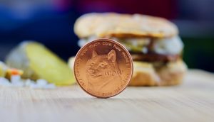 Dogecoin-Münze, im Hintergrund ein Burger