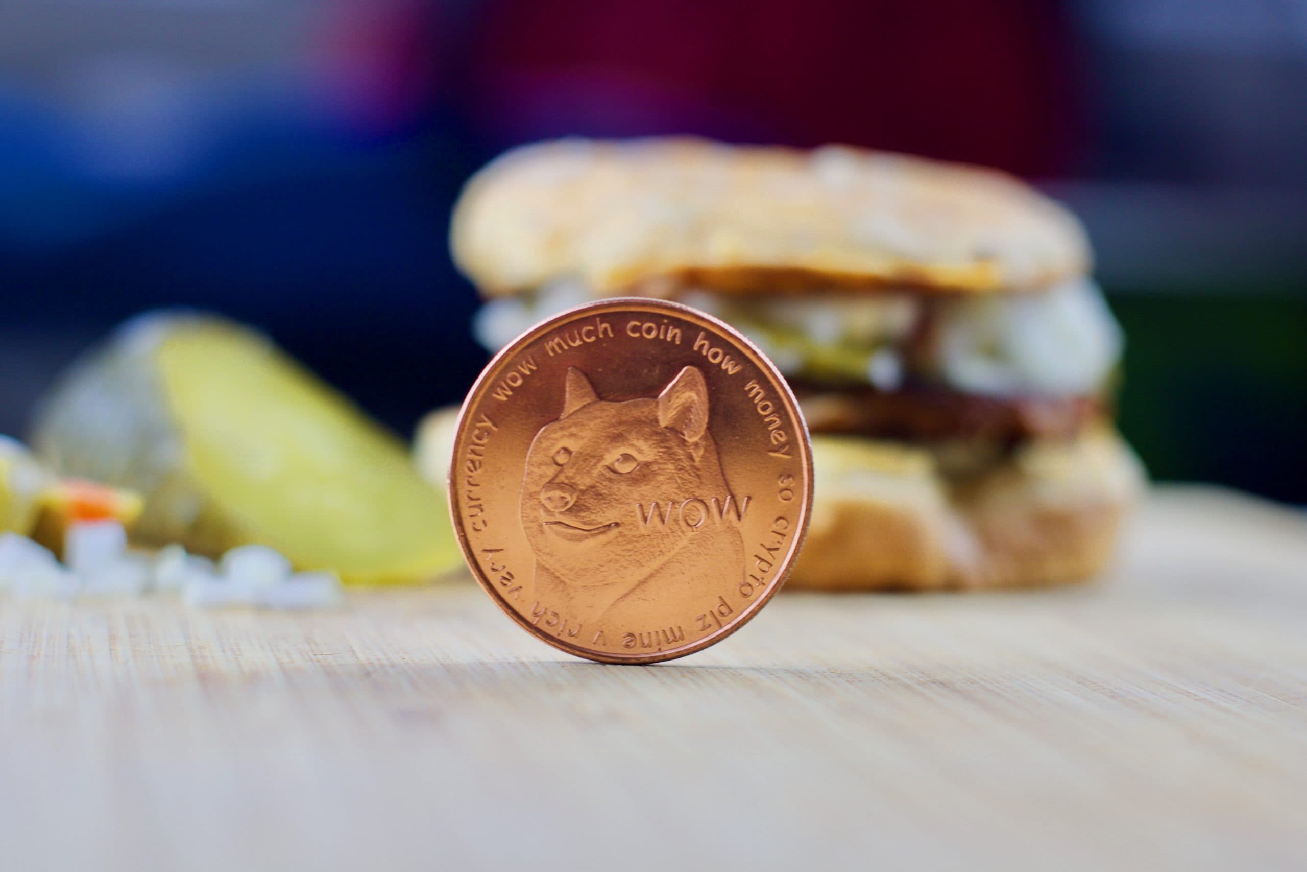 Dogecoin-Münze, im Hintergrund ein Burger