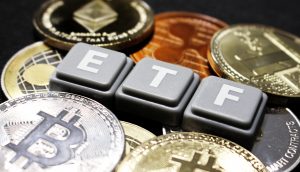 Mehrere Krypto-Münzen auf einem Tisch. In der Mitte steht in Großbuchstaben "ETF".