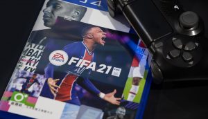 Das Cover von Fifa 21, daneben ist ein PS4-Controller.