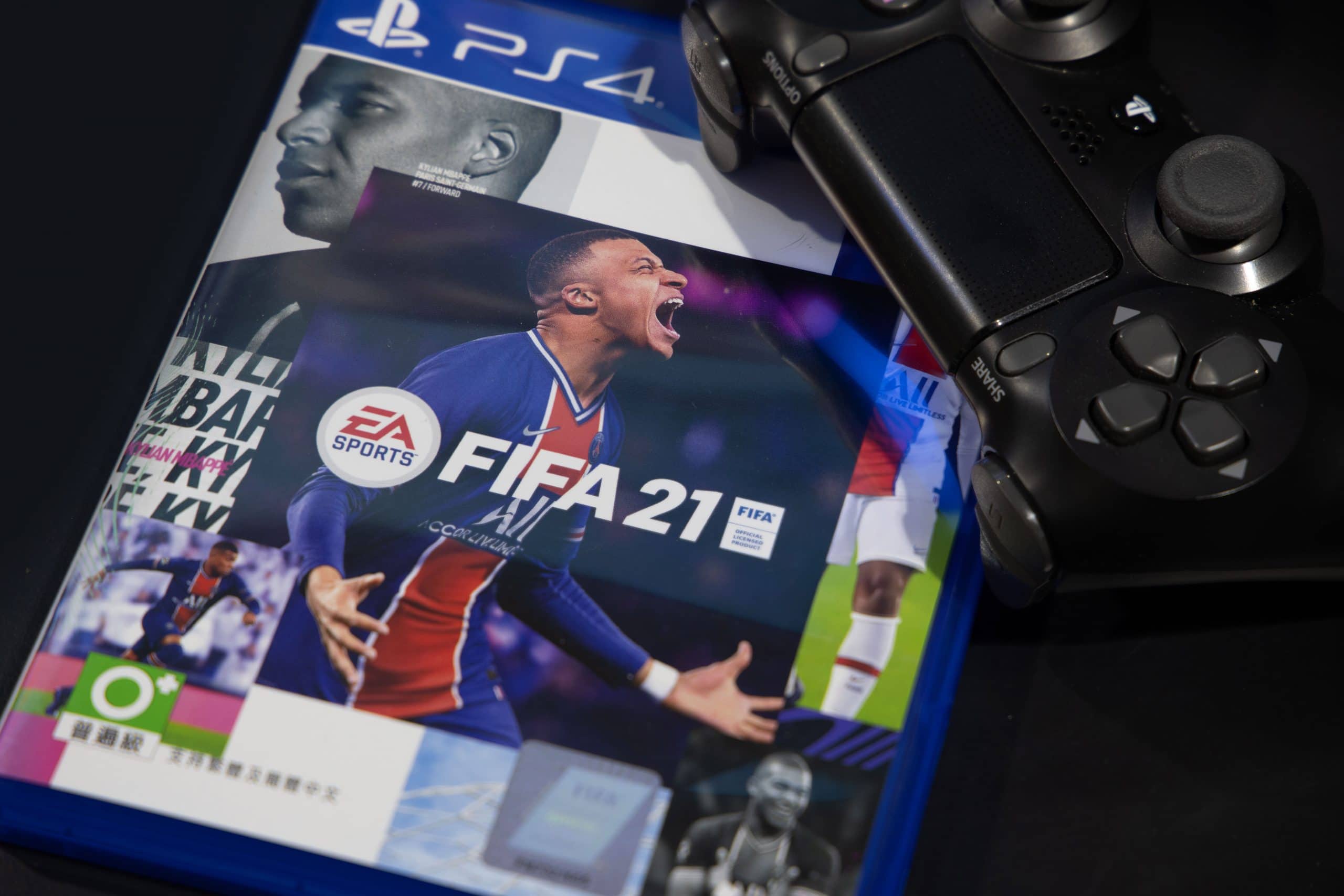 Das Cover von Fifa 21, daneben ist ein PS4-Controller.