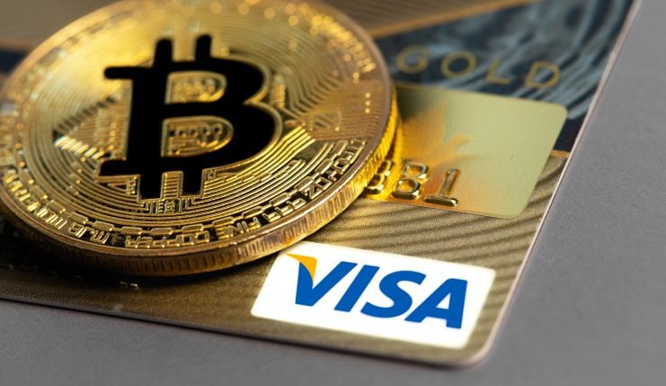 Ein Bitcoin liegt auf einer Visa-Karte