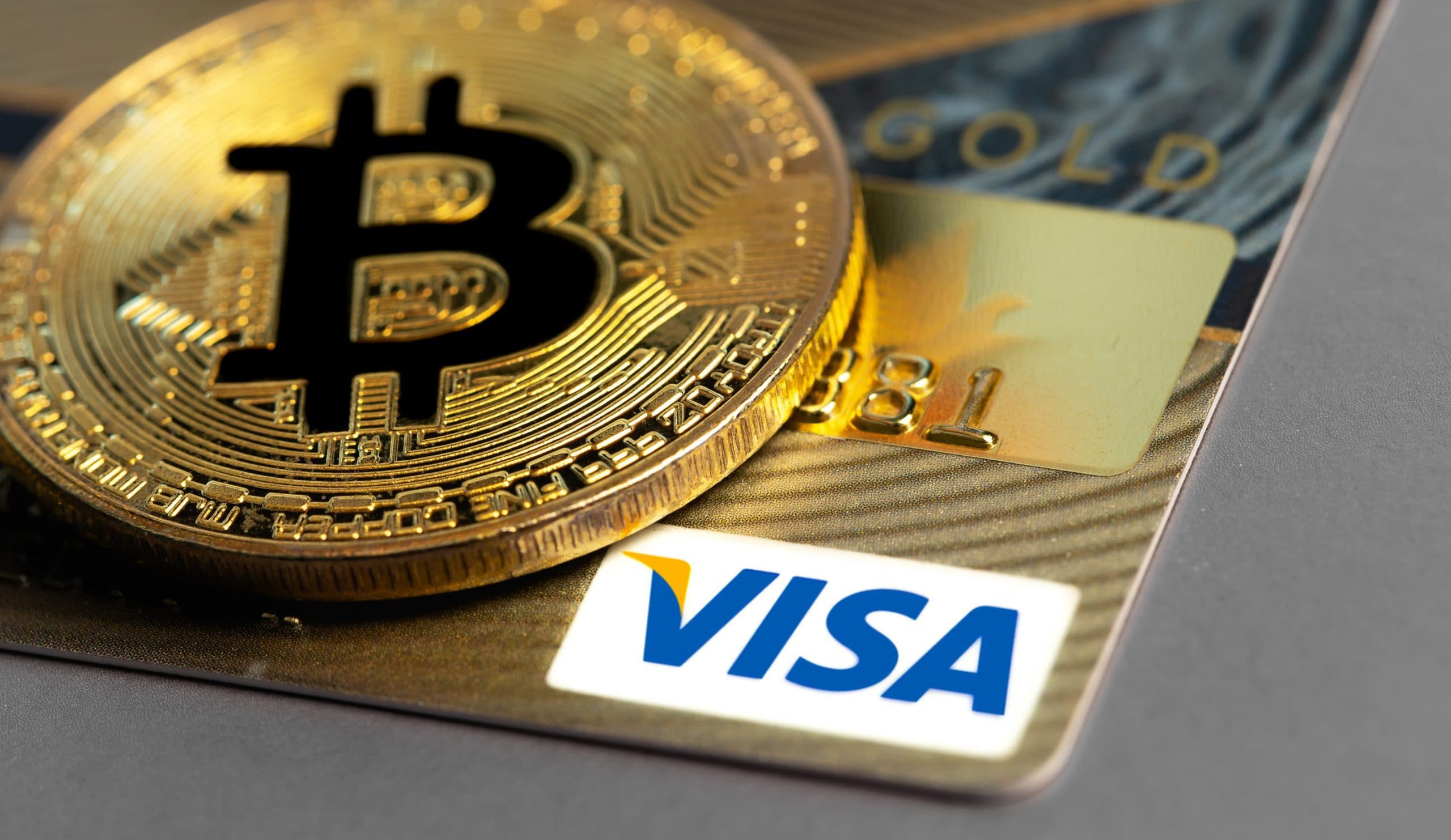 Ein Bitcoin liegt auf einer Visa-Karte