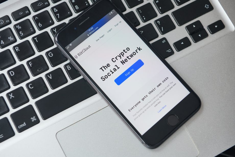 Social Token: BitClout (CLOUT) an Krypto-Börse AscendEX gelistet Ein Handy liegt auf einem Laptop. Darauf ist die BitClout-Plattform zu sehen.