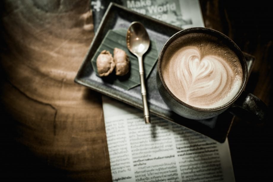 Alles im Blick: Die wichtigsten Krypto-News der Woche Eine Kaffeetasse steht auf einem Tablett mit Löffel und Keksen, das auf einer Zeitung steht.
