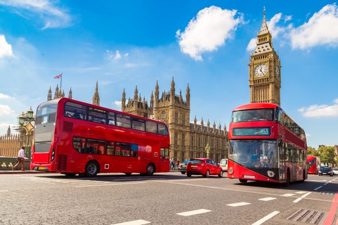 Zwei Busse in London vor der Westminster Abbey und dem Big Ben.