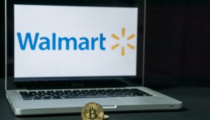 Bitcoin-Münze liegt vor einem Laptop mit Walmart-Logo