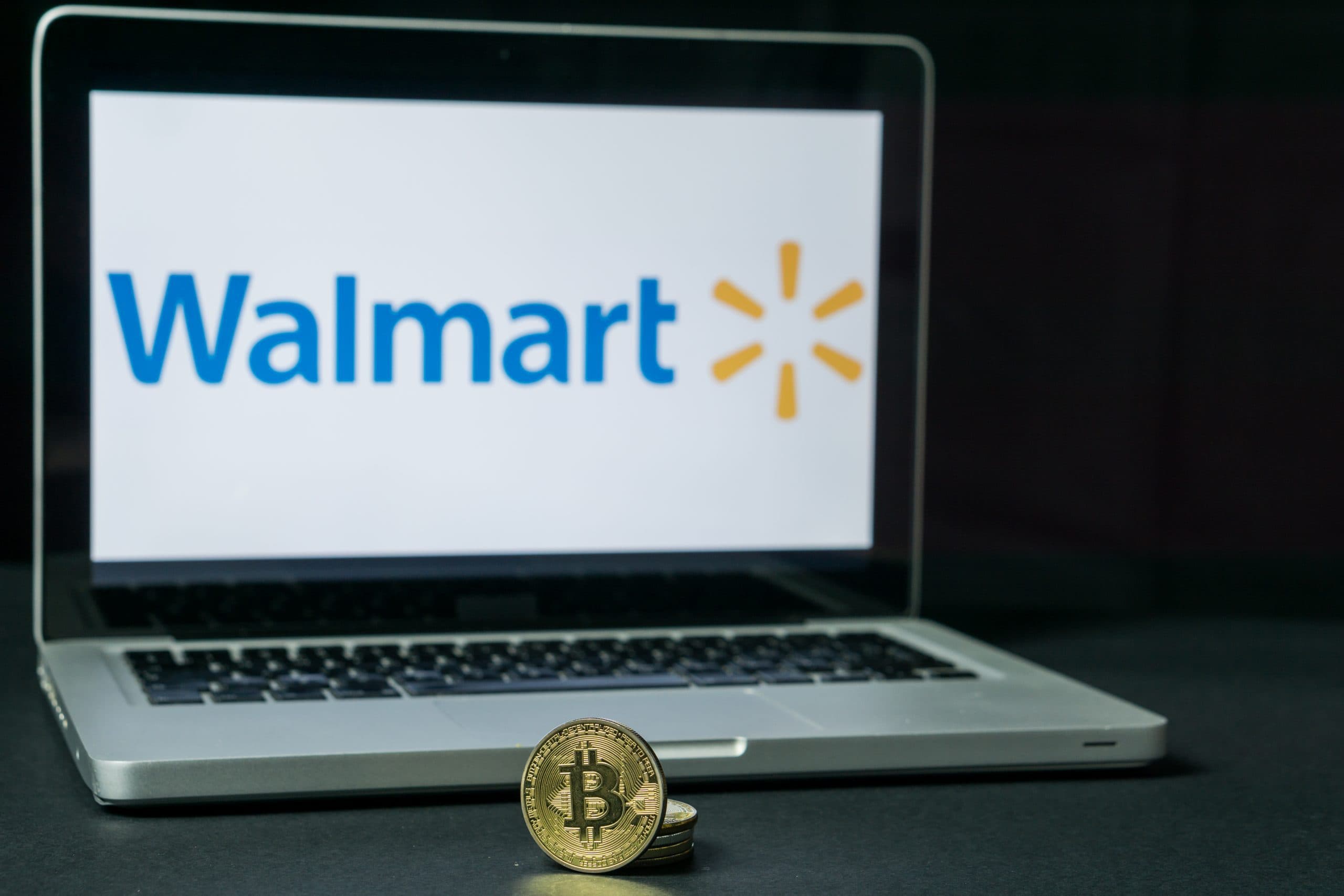 Bitcoin-Münze liegt vor einem Laptop mit Walmart-Logo