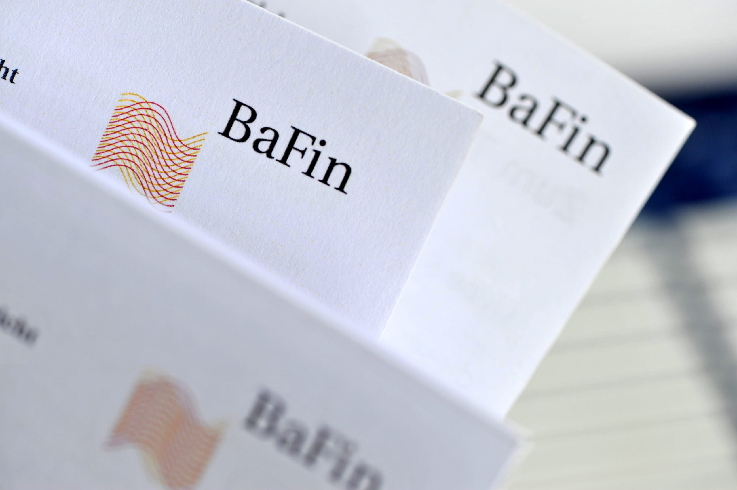 Das Logo der BaFin auf mehreren Papierseiten.