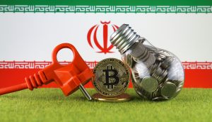 Eine Bitcoin-Münze steht neben einem Ladekabel und einer mit Münzen gefüllten Glühbirne
