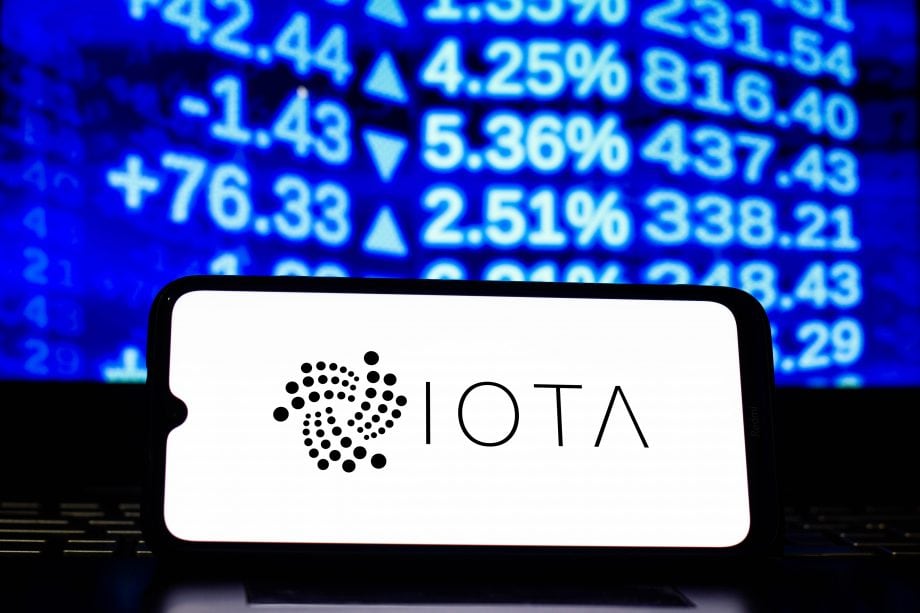 Dank Partnerschaft: IOTA will KYC-Prozesse revolutionieren IOTA-Logo auf Smartphone vor Kurs-Ticker.