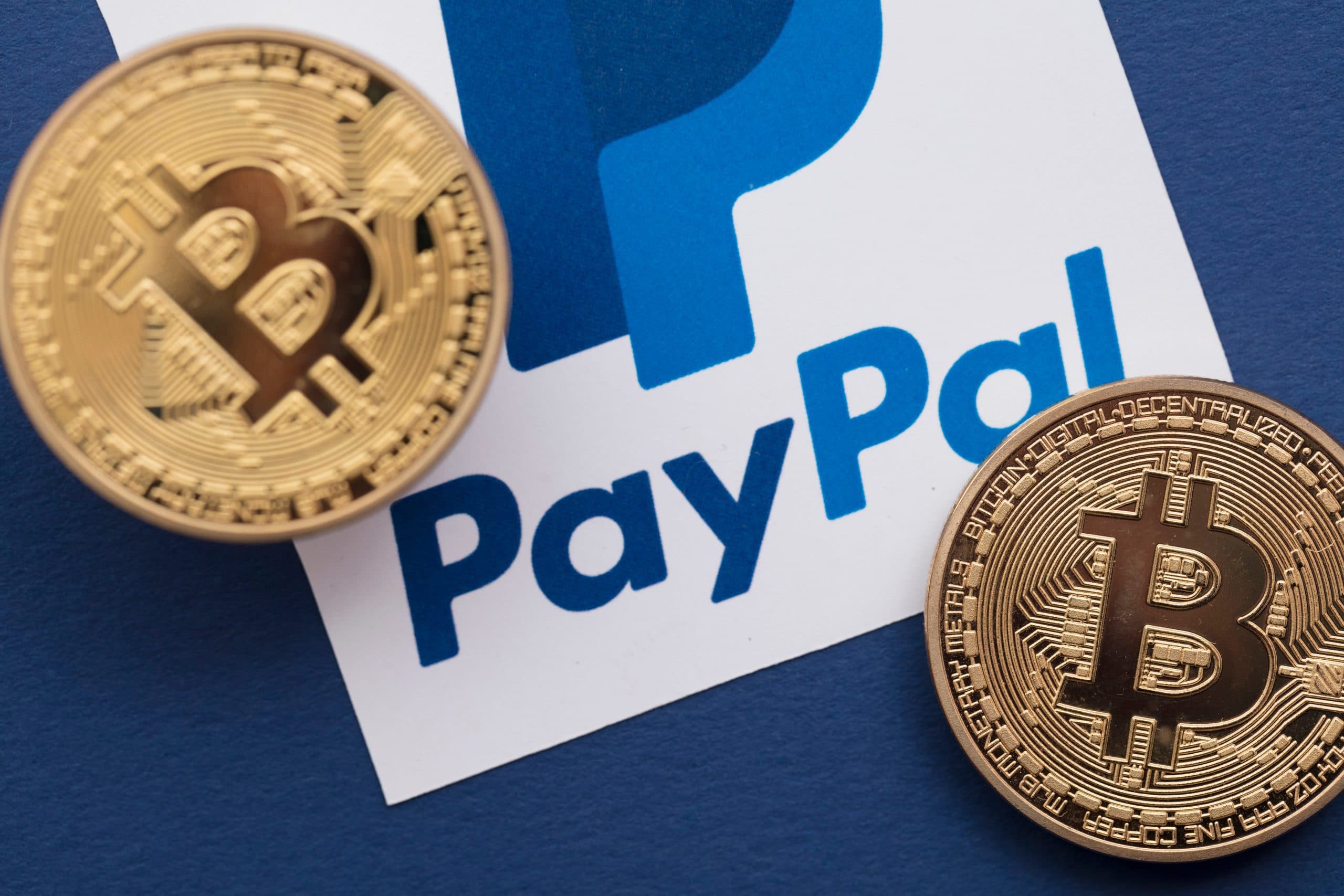 Zwei Bitcoin-Münzen neben dem PayPal-Logo