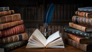 Aufgeschlagenes Buch liegt auf einem Tisch, umringt von Bücherstapeln