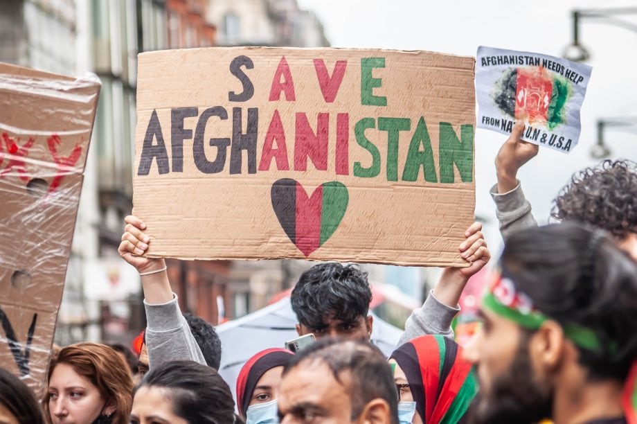 Erlöse aus NFT Versteigerung für humanitäre Hilfe in Afghanistan Save Afghanistan in schwarz, rot, grün geschrieben auf einem Pappschild wird in mitten einer Menschenmenge hoch gehalten