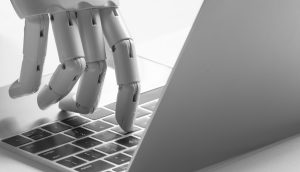 Eine Roboter Hand tippt auf einem Laptop