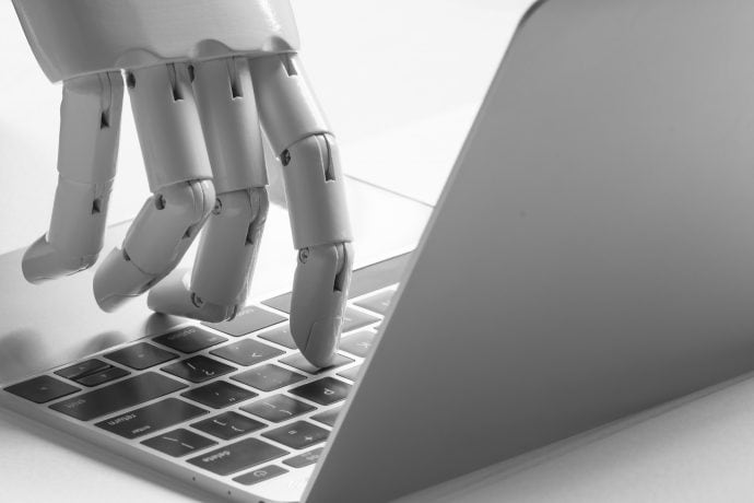 Eine Roboter Hand tippt auf einem Laptop