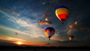 Mehrere Heißluftballons steigen in den Abendhimmel.