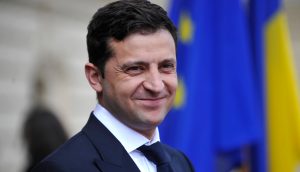 grinsender Präsident Zelensky, Ukraine mit Ukrainischer Flagge im Hintergrund