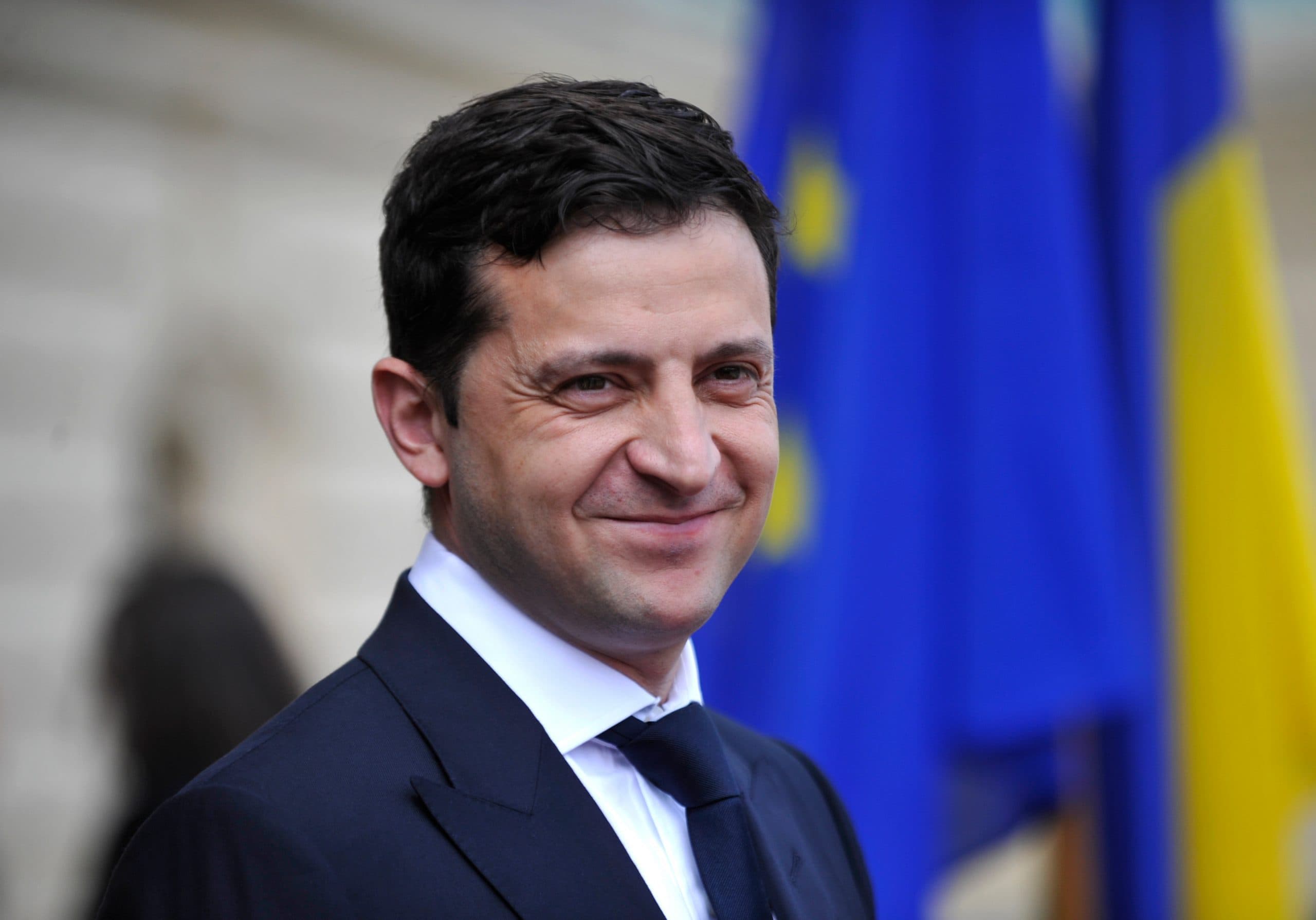 grinsender Präsident Zelensky, Ukraine mit Ukrainischer Flagge im Hintergrund