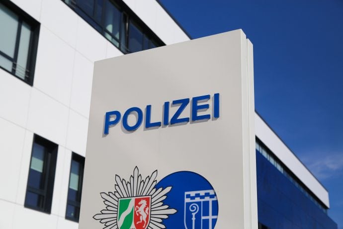 Bild des Polizei Schilds mit NRW Flagge darunter.