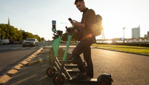 junger Mann mit Roller und Telefon