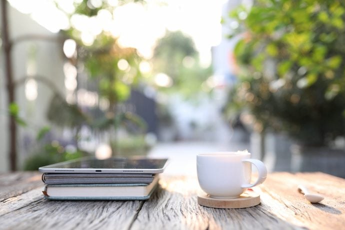 Kaffee, Buch und Tablet auf einem Tisch