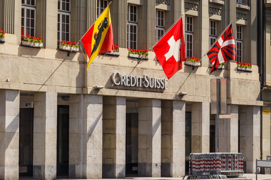 Schweiz: Aktien eines Start-ups auf Ethereum-Blockchain tokenisiert Schweizer Flagge vor Gebäude der Credit Suisse