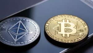 Münzen von Bitcoin und Ethereum liegen auf einem Smartphone