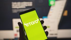 Hand hält Smartphone mit eToro-Logo
