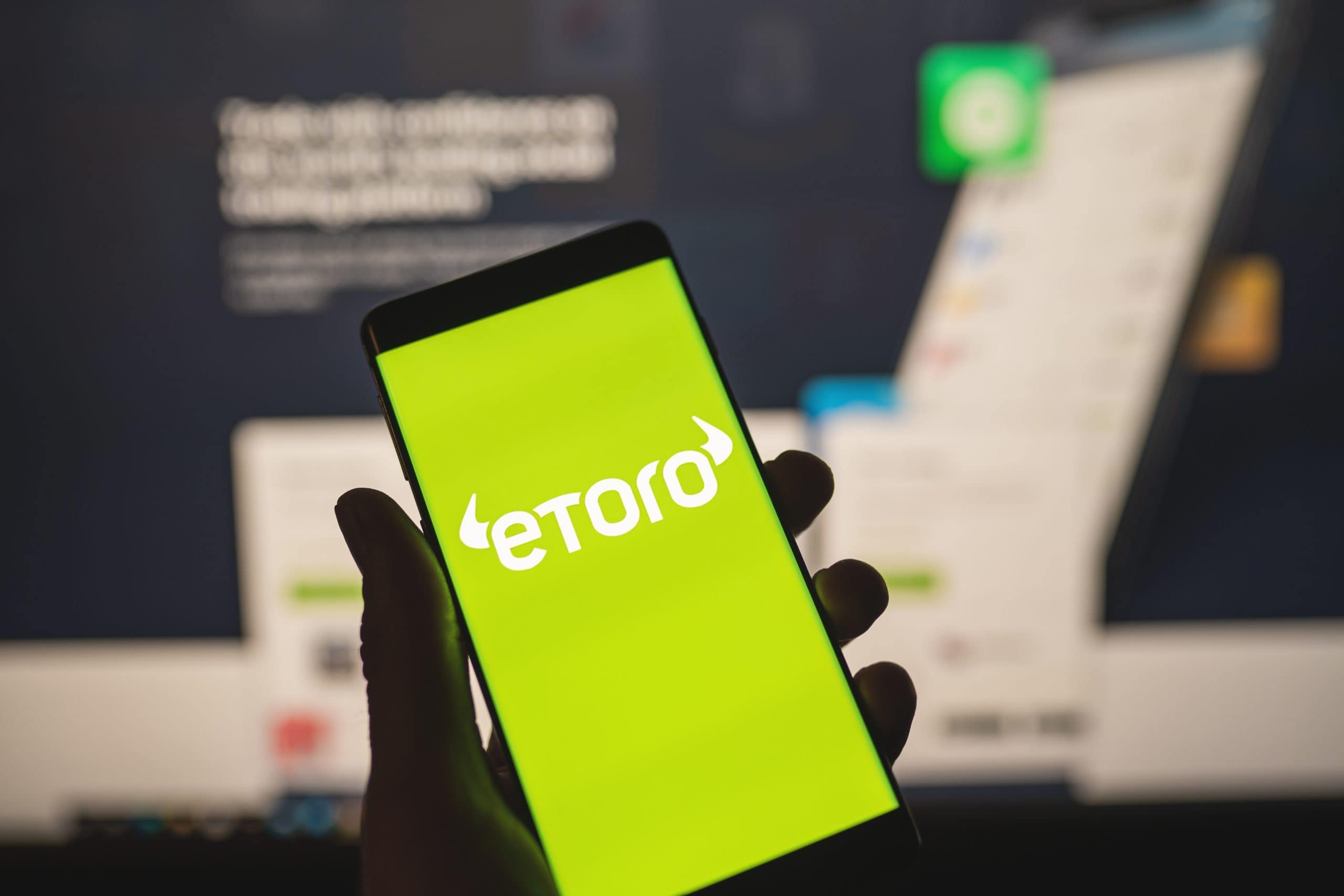 Hand hält Smartphone mit eToro-Logo