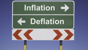 Schild gegen blauen Himmel. Nach links wird Deflation, nach rechts Inflation ausgewiesen.