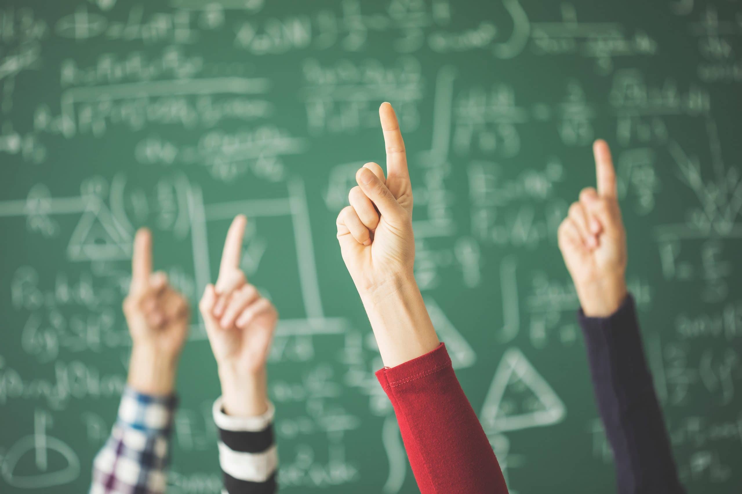 Schüler heben Finger im Klassenraum