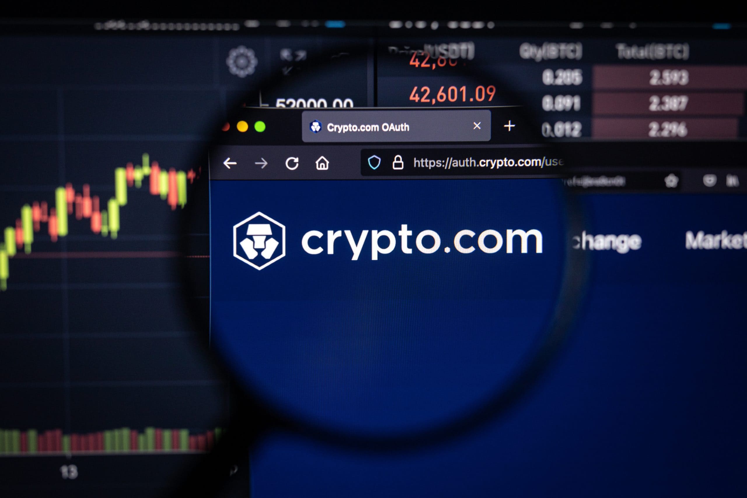 Eine Lupe fokussiert auf das Logo und die Website von crypto.com, die auf einem Computerbildschirm angezeigt werden, eingerahmt von Finanzdiagrammen und dynamischen Marktdaten.