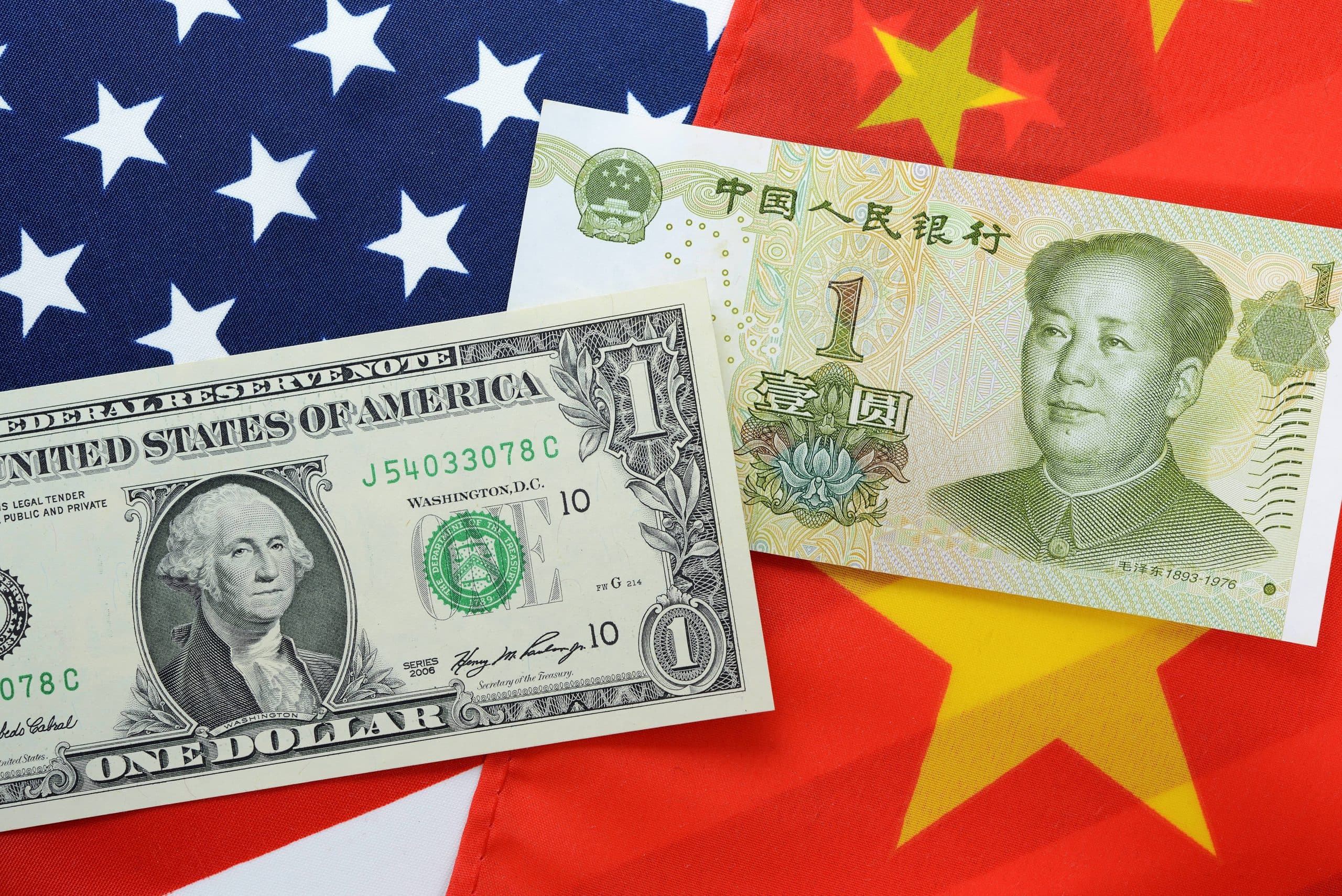 Dollar und Renminbi vor amerikanischer und chinesischer Flagge
