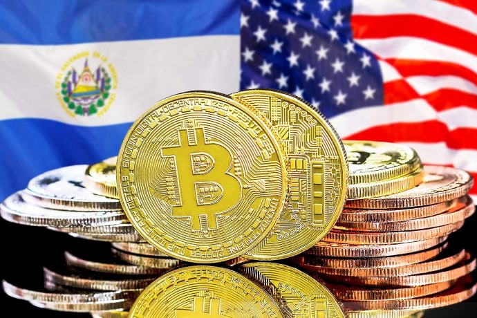 Bitcoin Münzen vor den Flaggen der USA und El Salvador