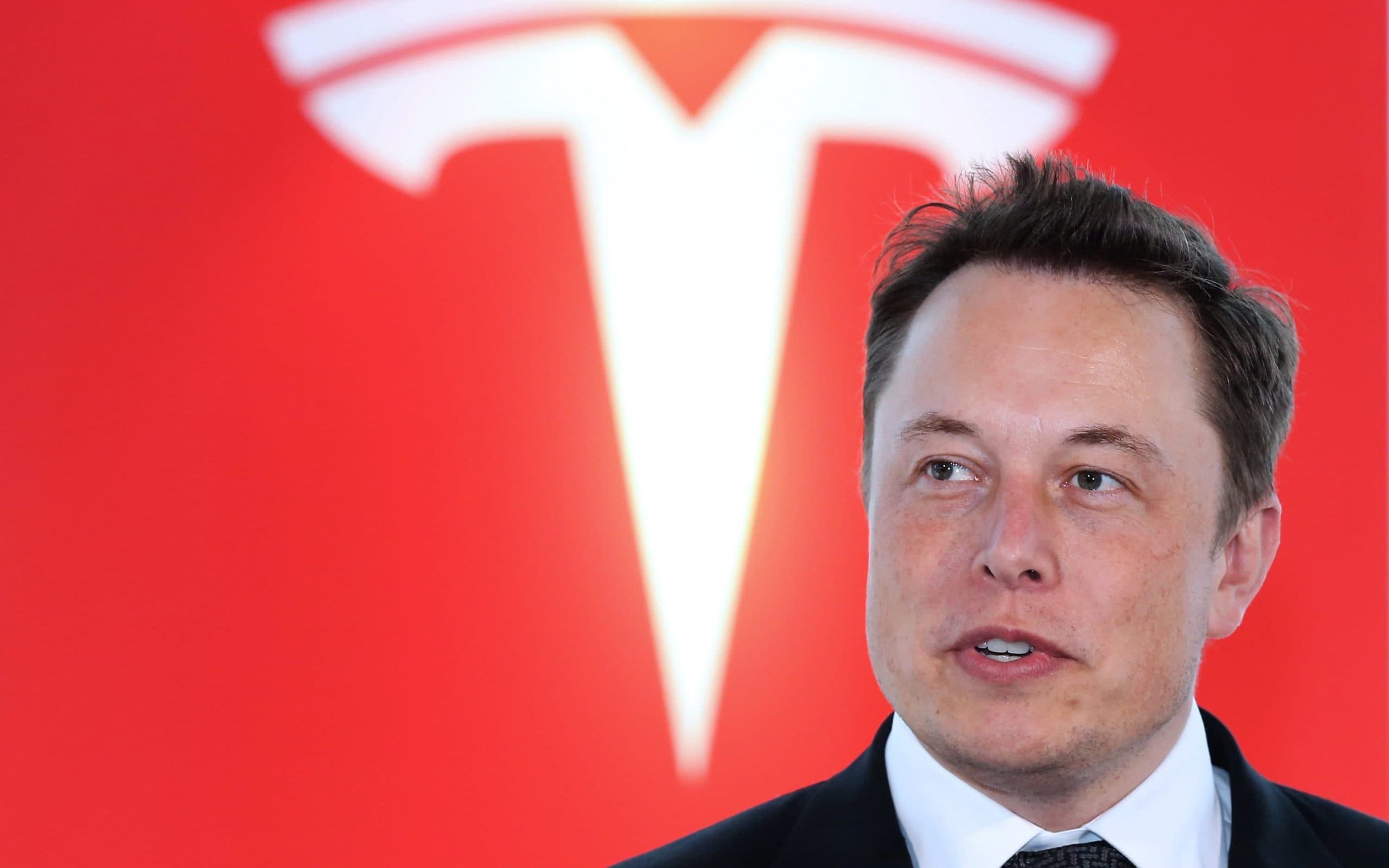 Elon Musk vor rotem Tesla-Logo