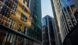 Bitcoin-Symbol auf einer Wand eines großen Bank-Gebäudes neben weiteren Gebäuden