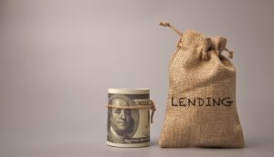 Geldsack neben US-Dollar-Bündel.
