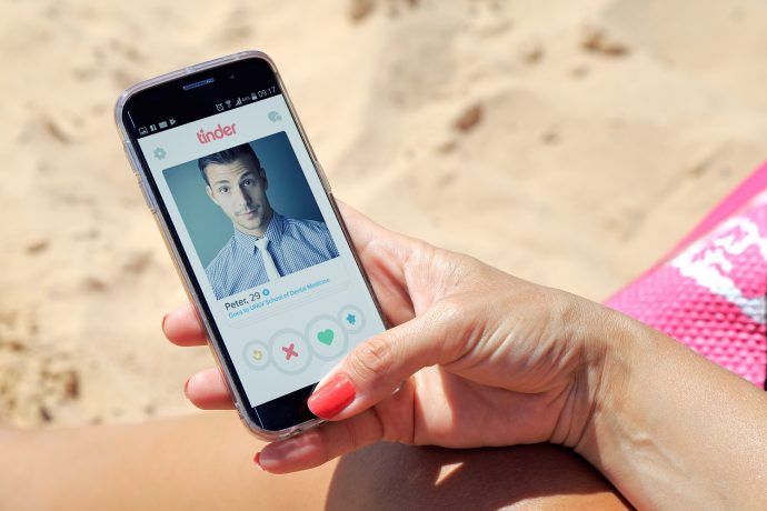 Hand mit einem Smartphone, auf dem die Tinder-App geöffnet ist