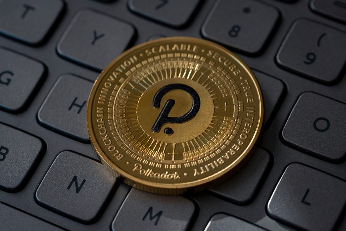 Die goldene Polkadot-Kryptowährungsmünze liegt auf einer schwarzen Tastatur und zeigt das ikonische Polkadot-Logo. Am Rand steht stolz „BLOCKCHAIN INNOVATION SCALABLE SECURE TRUE INTEROPERABILITY“ und unterstreicht damit die Essenz der Vision von Polkadot.