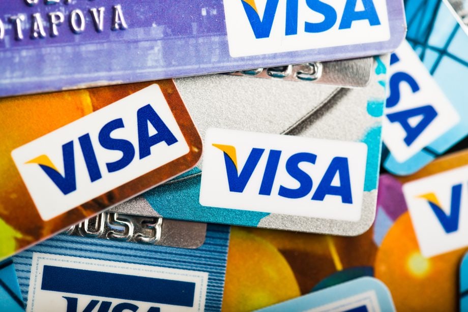Mehrere Visa-Kreditkarten sind gestapelt und überlappend angeordnet, wobei das Visa-Logo auf jeder Karte in verschiedenen Farben und einzigartigen Designs deutlich sichtbar abgebildet ist.