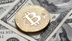 Eine glänzende goldene Bitcoin-Münze liegt auf einem Stapel US-Dollarscheine, darunter ein gut sichtbarer 100-Dollar-Schein, und veranschaulicht die Mischung aus traditioneller und digitaler Währung.