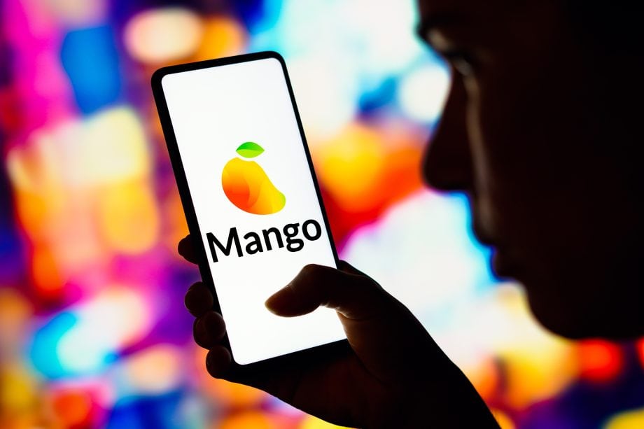 Eine Person hält ein Smartphone, auf dessen Bildschirm das Logo der Mango-App angezeigt wird, mit einem farbenfrohen abstrakten Hintergrund, der von Mango Markets inspiriert ist.