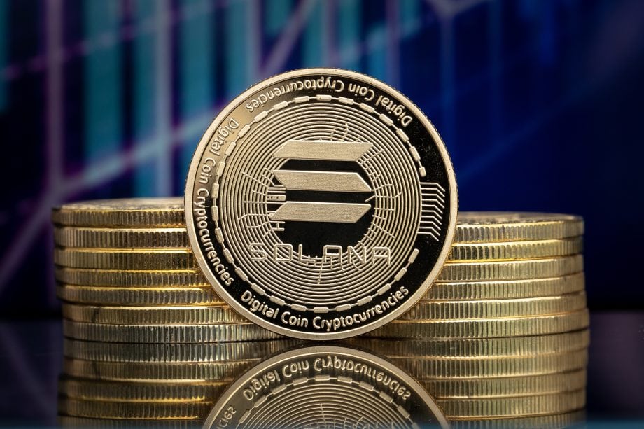 Ein Stapel goldfarbener Münzen, vor dem aufrecht eine Solana-Kryptowährungsmünze mit dem unverwechselbaren Solana-Logo und dem digitalen Schaltkreisdesign steht.